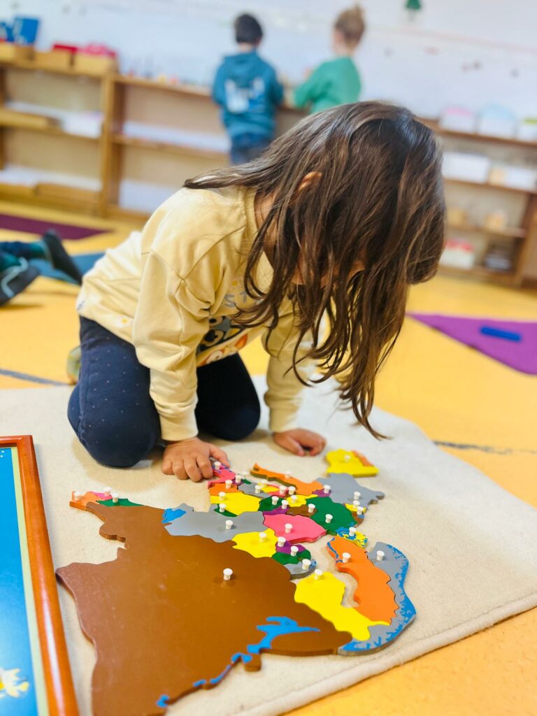 Une enfant explore une carte du monde avec du matériel Montessori