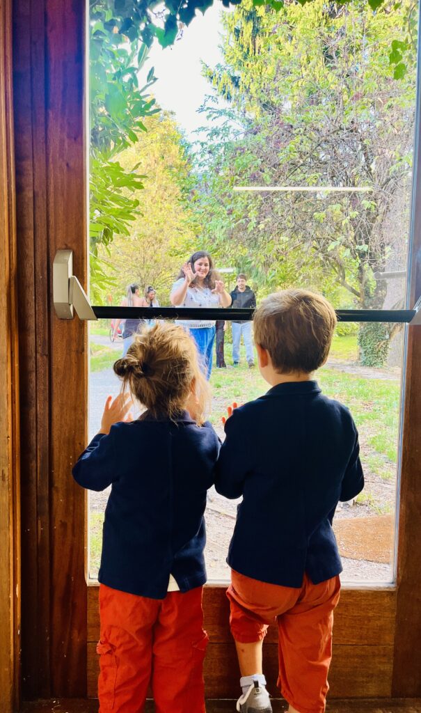 Deux enfants accueillent une adulte dans le jardin de l’école Montessori à Grenoble